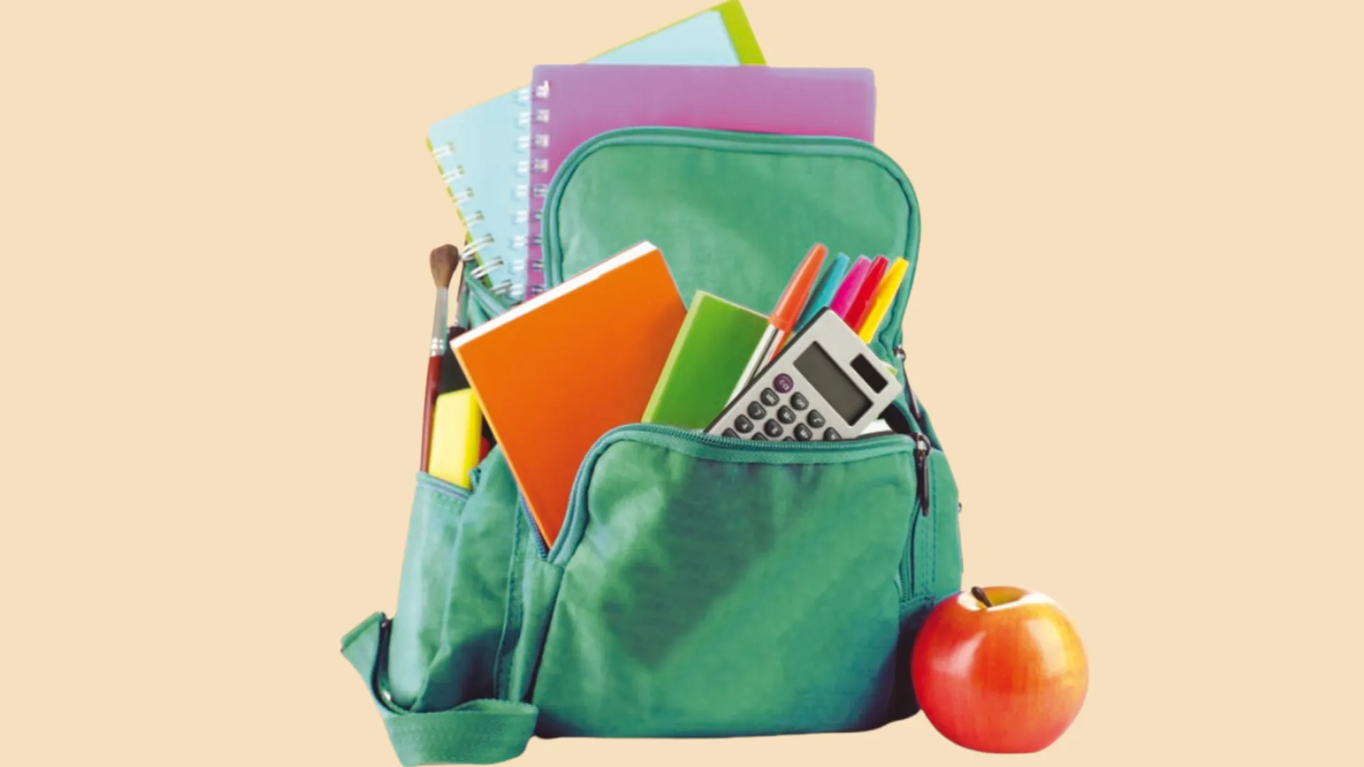 A green school bag filled with notebooks, pens, a calculator, and an apple