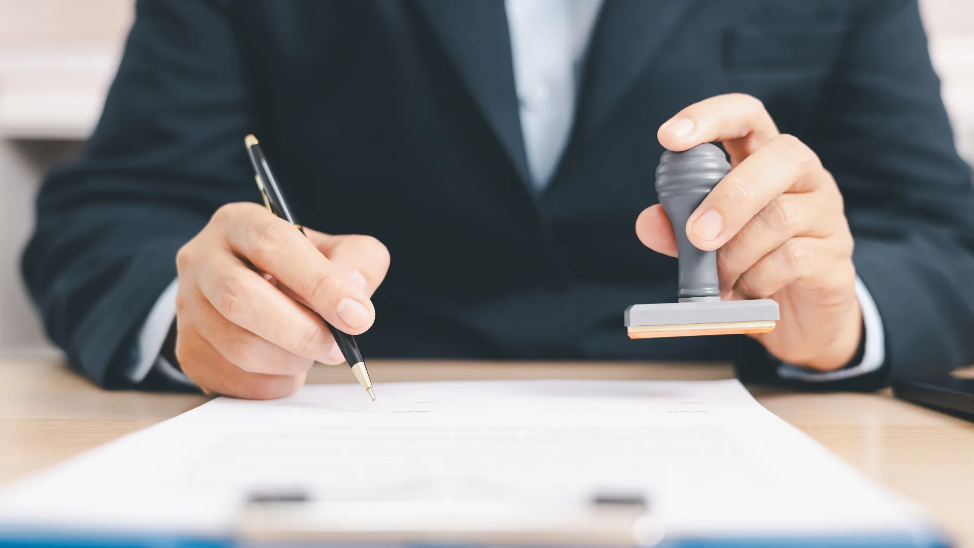 Person signing and stamping a document.