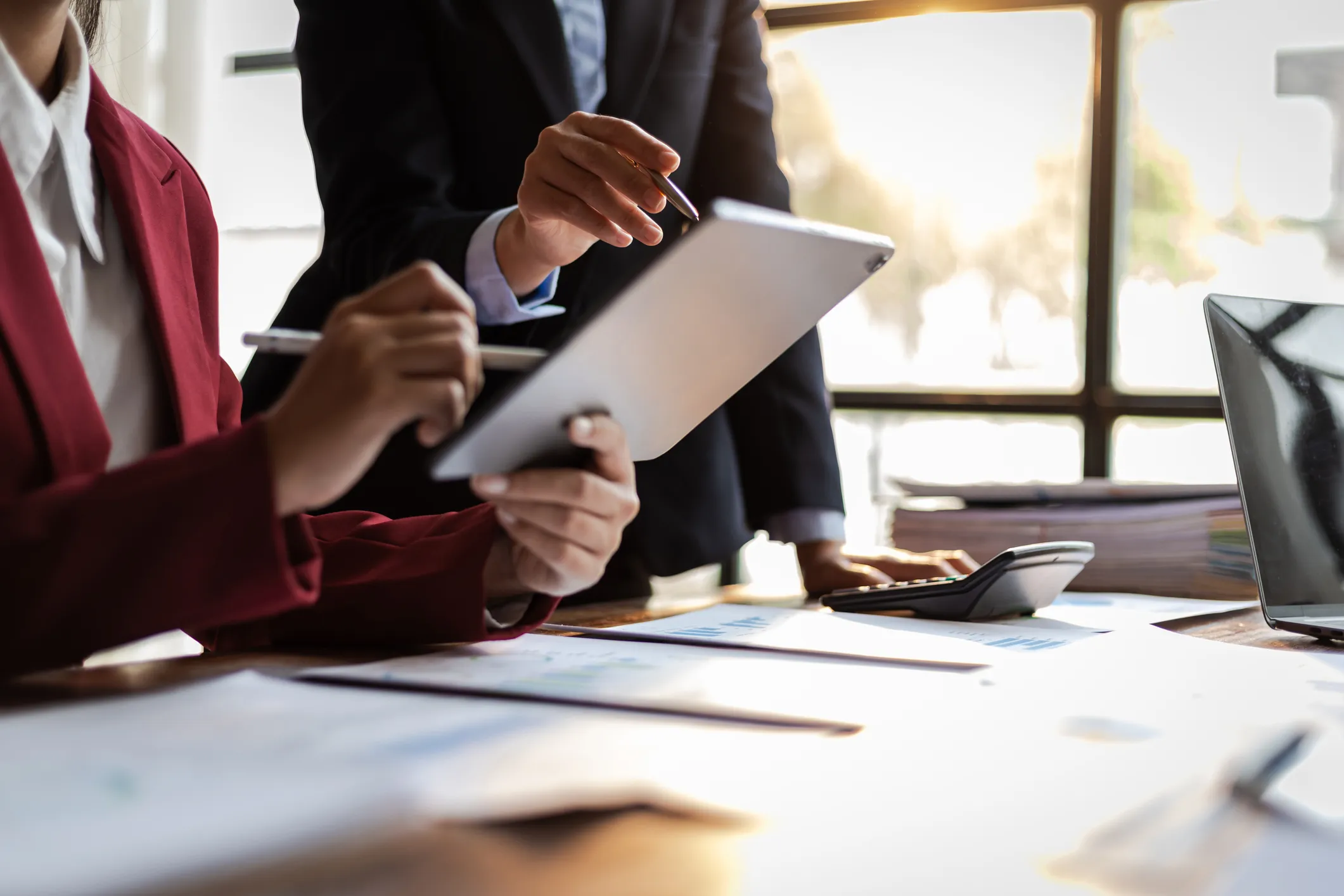 Two professionals reviewing information on a tablet at a desk