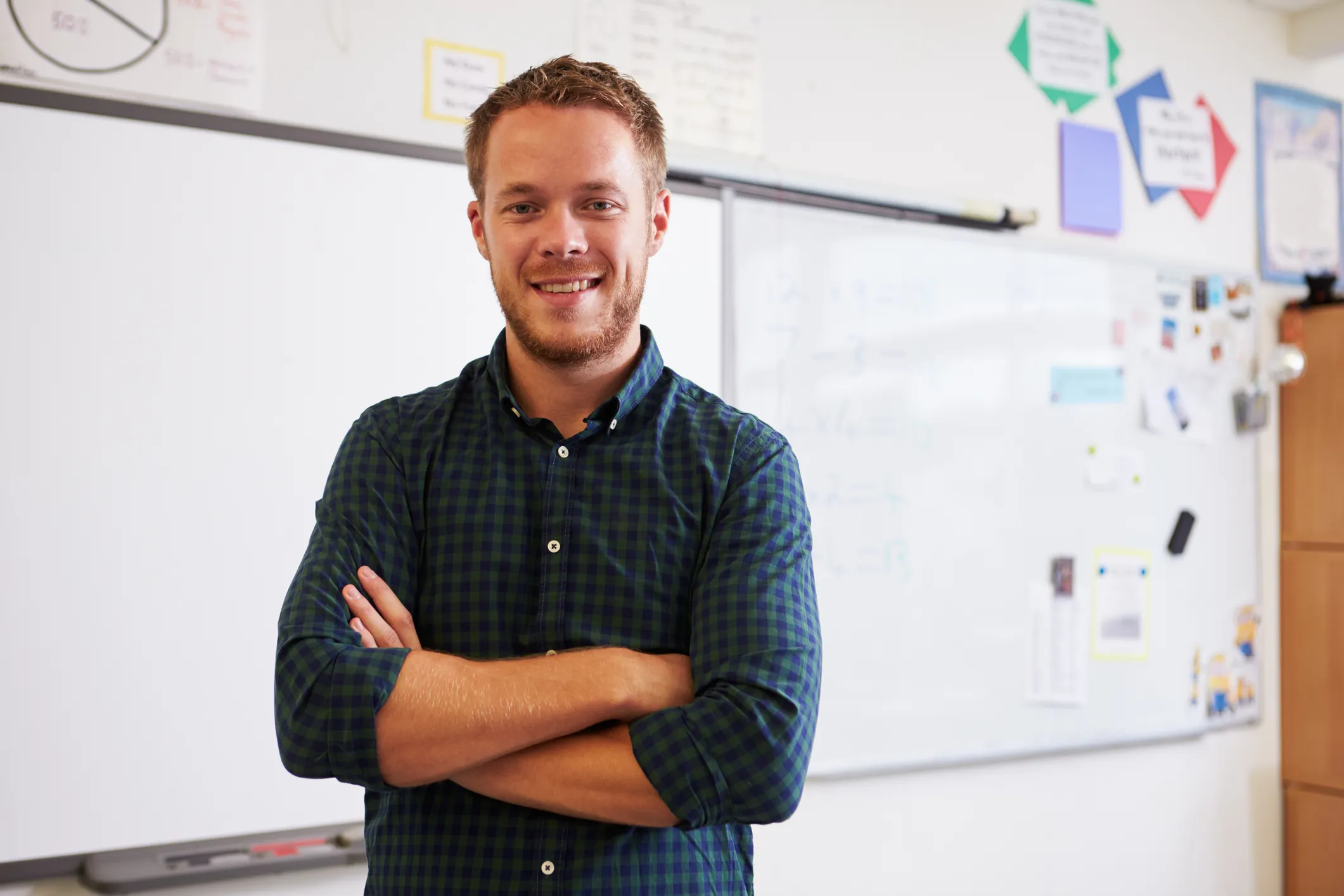 Person stands with arms crossed in a classroom