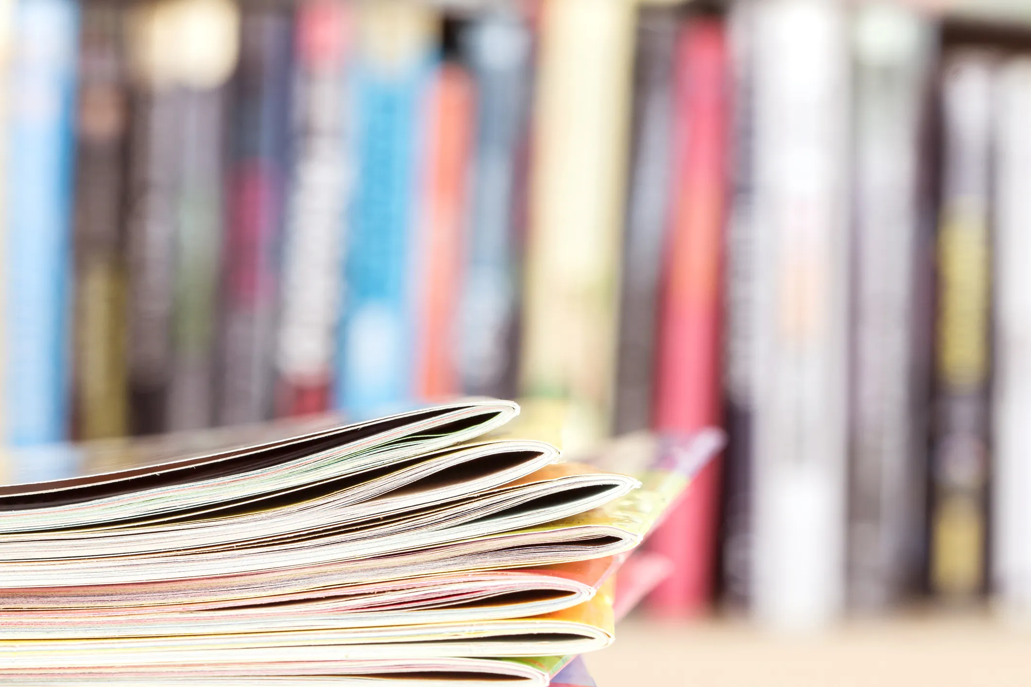 Stack of publications with blurred bookshelf in background.