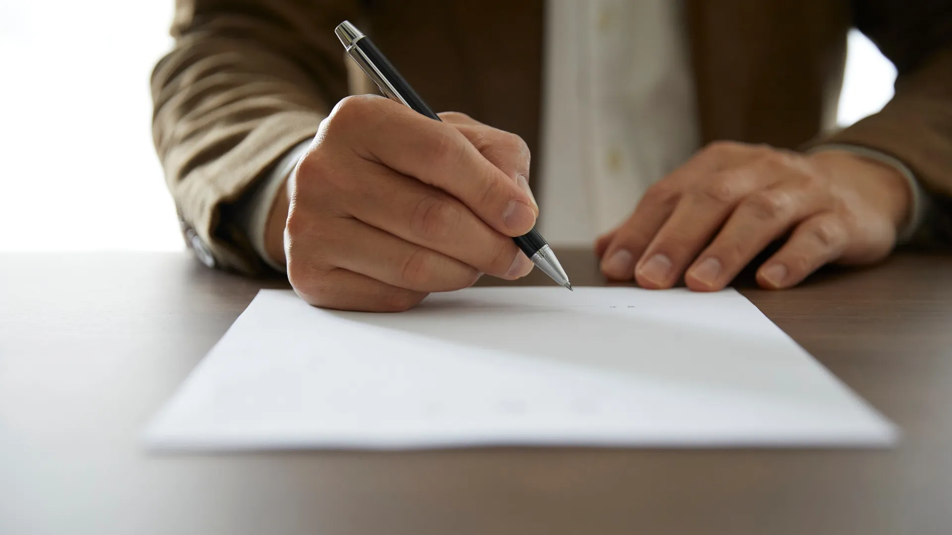 Person signing a document at a desk.