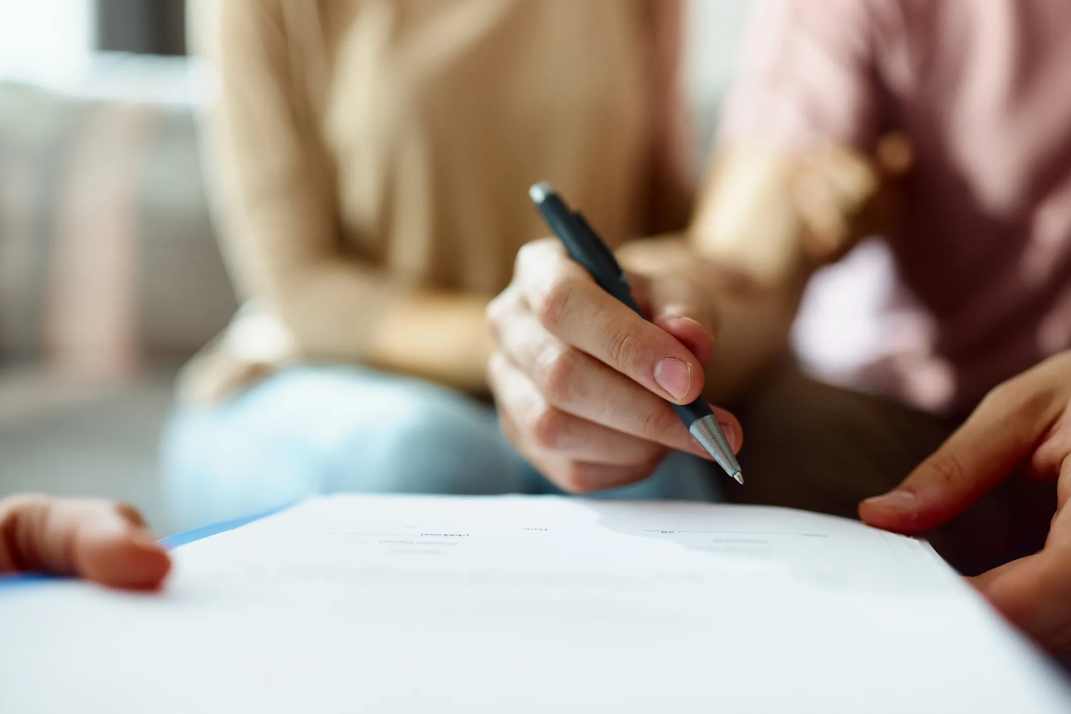 Person holding a pen and signing a document