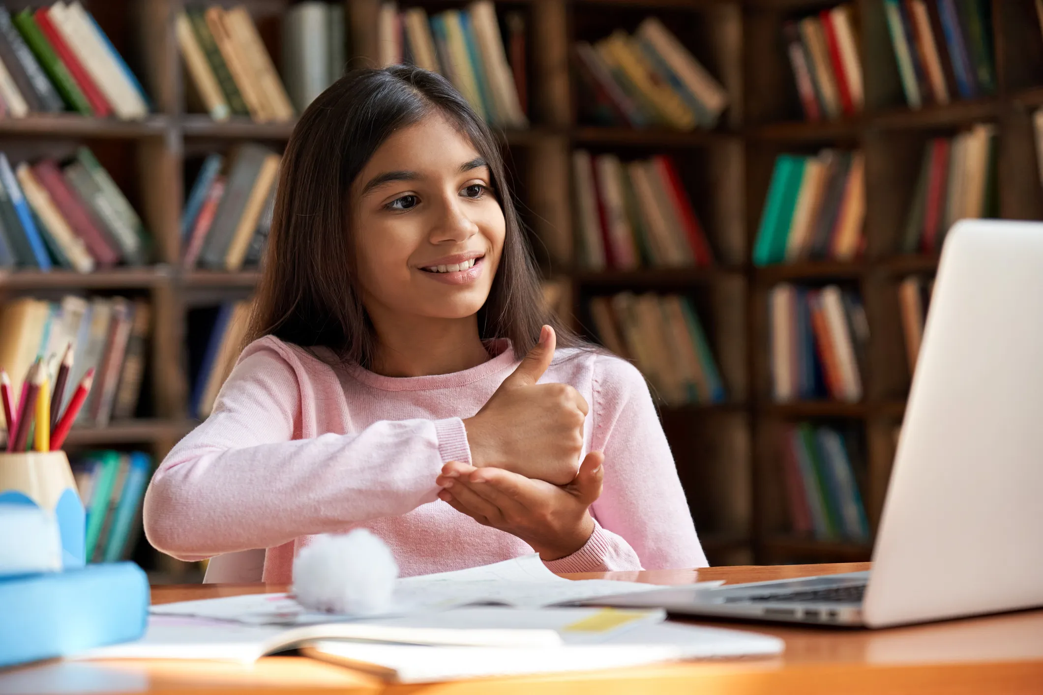 Child using sign language to communicate during an online meeting