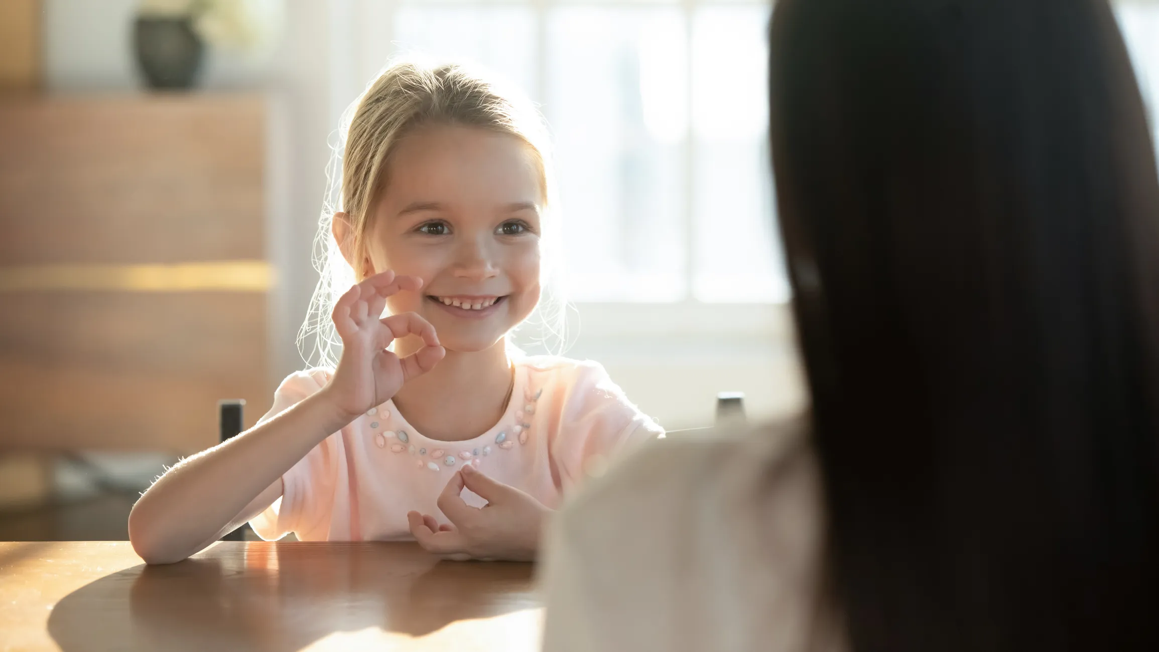 Child using sign language to communicate with an adult