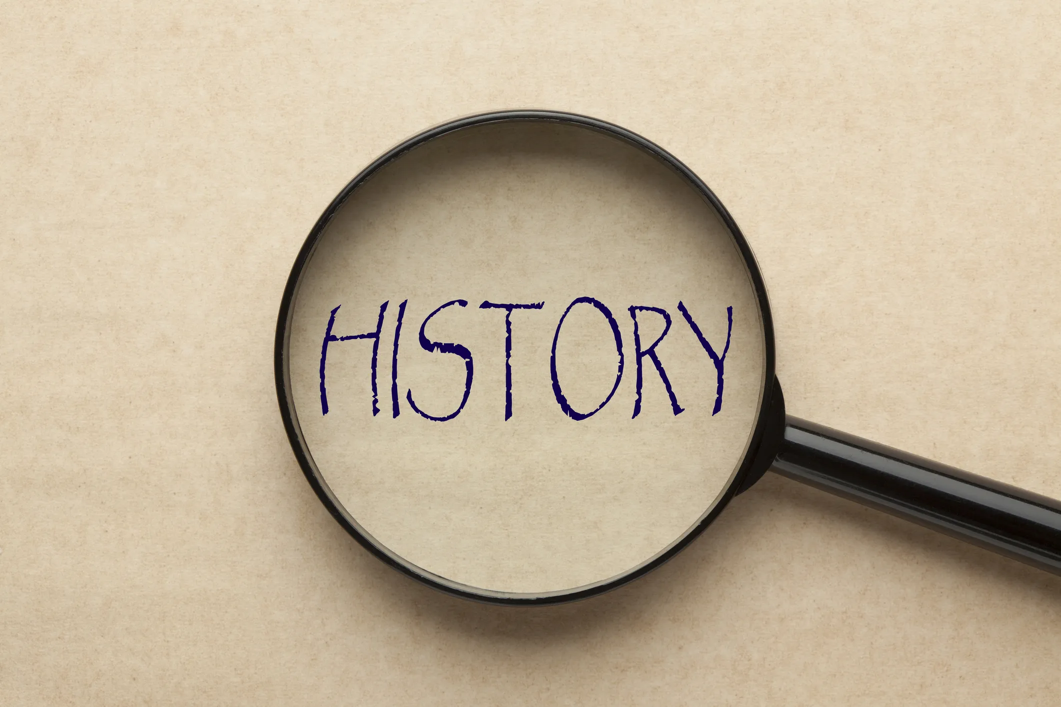 Magnifying glass enlarging the word "HISTORY" on a beige background