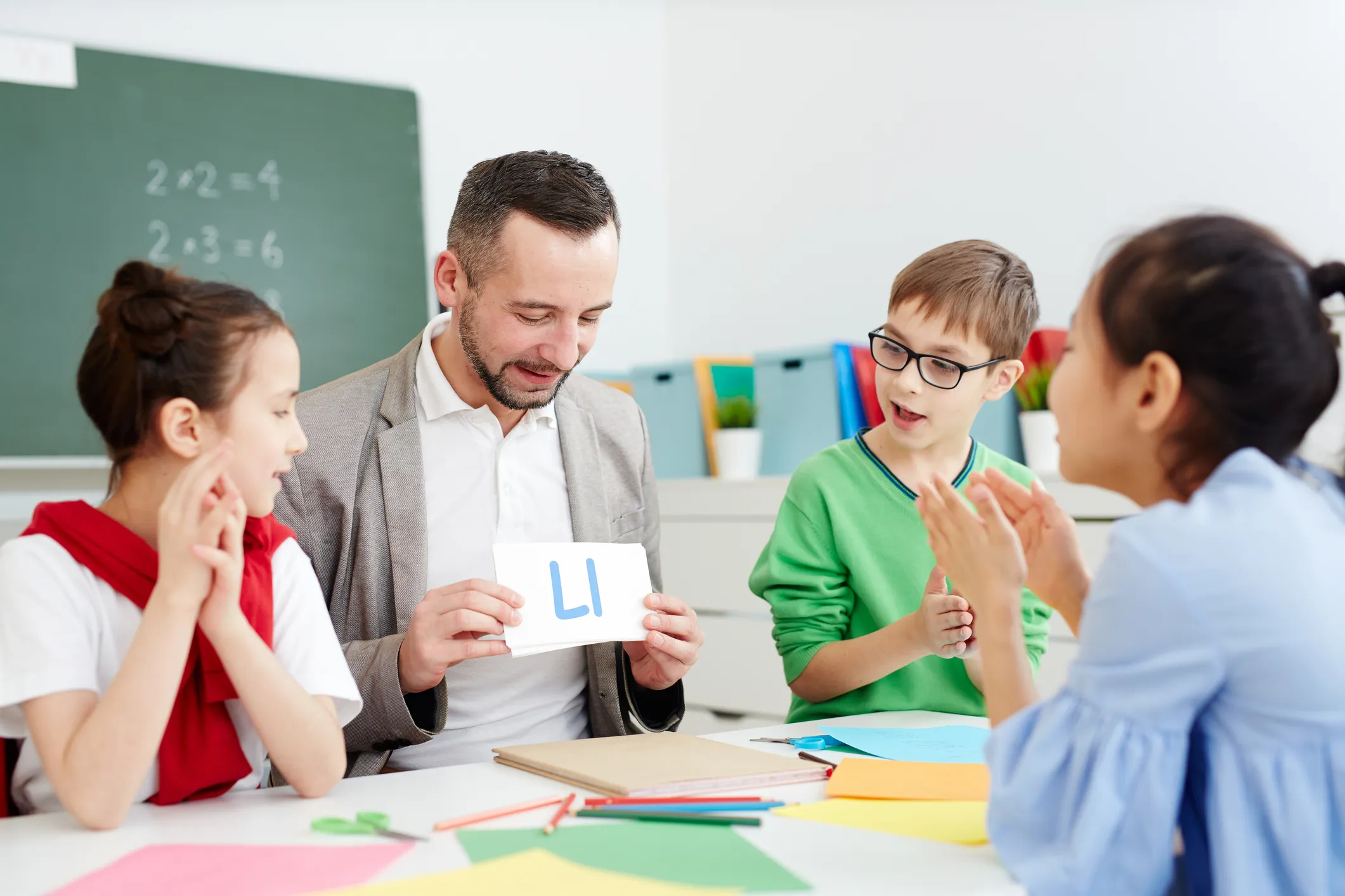 Teacher using a flashcard with "LI" to teach children in a classroom