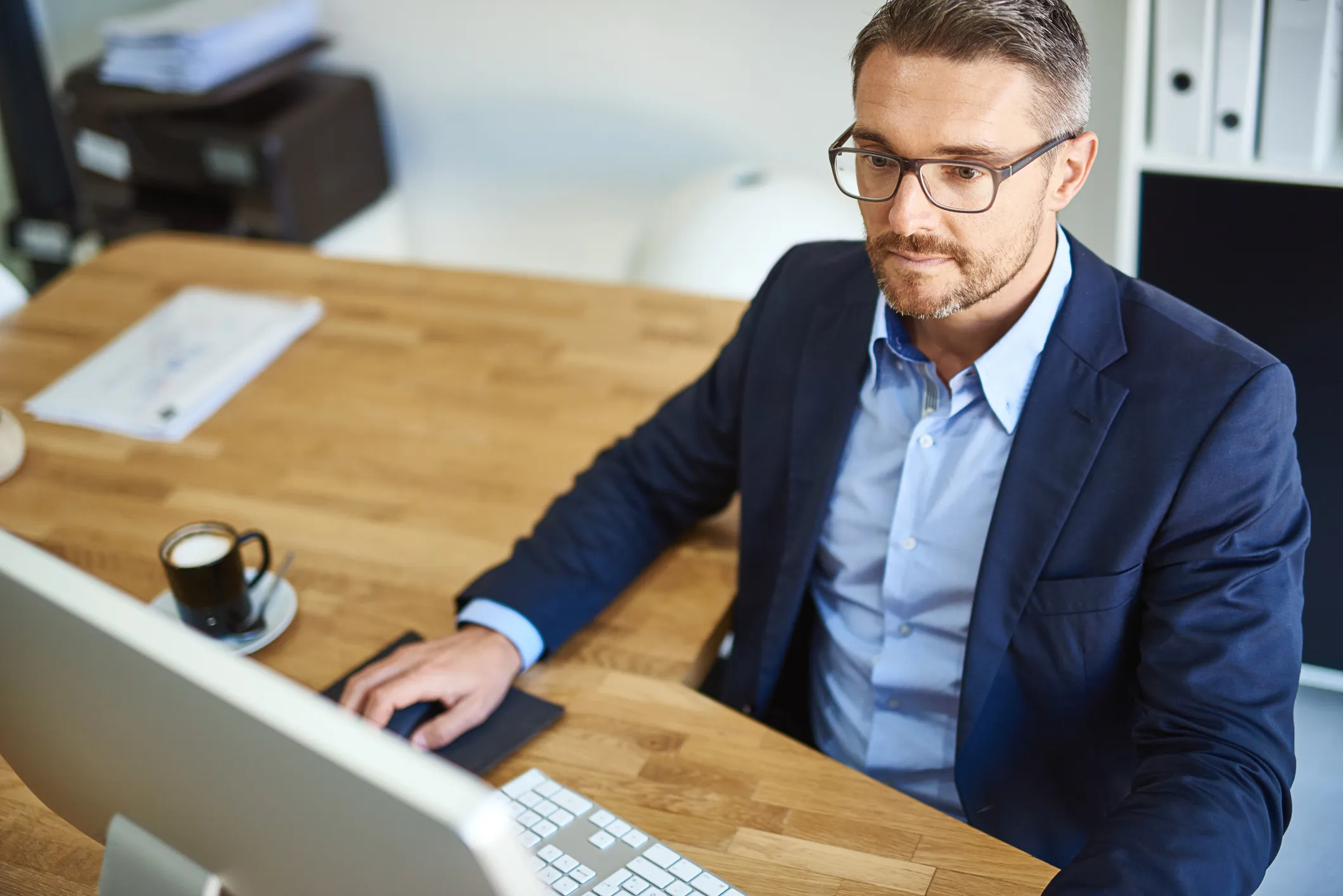 Person working at a desk with a computer and coffee cup