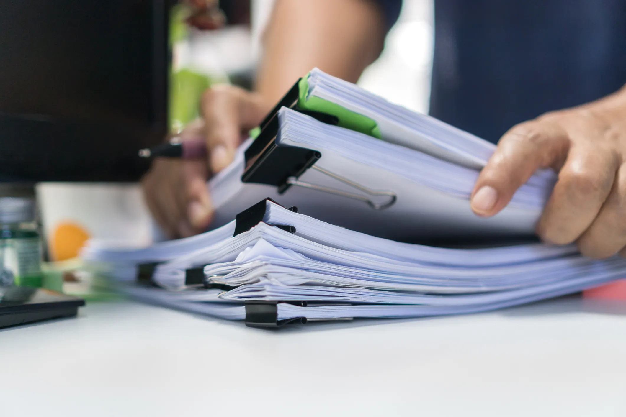 Person handling a stack of clipped documents on a desk