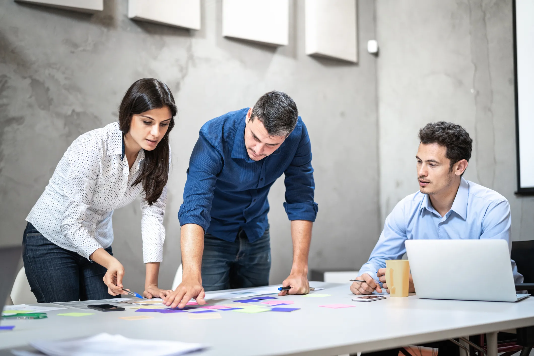 Three people are gathered around a table in a office setting