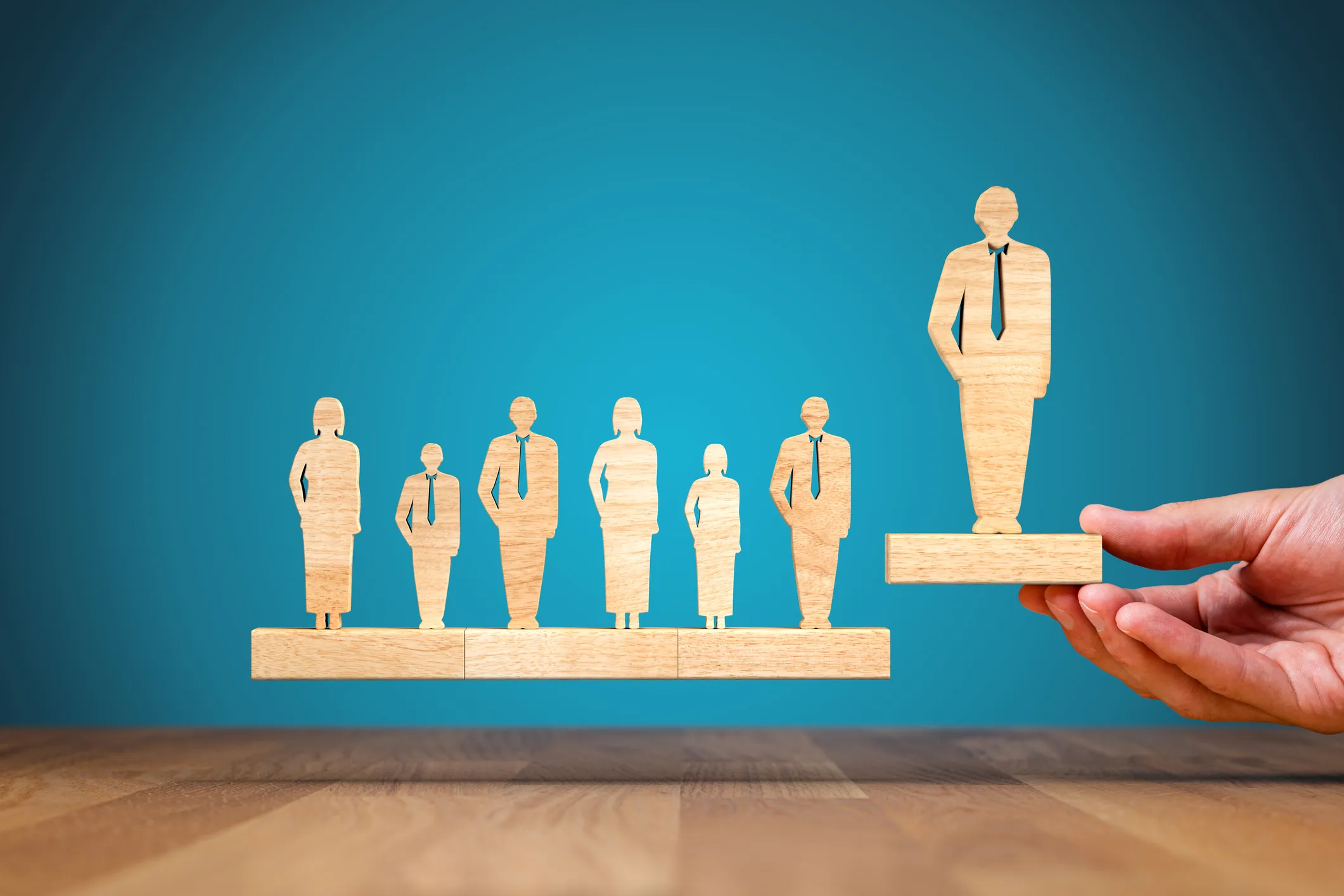 Wooden figures of people with one elevated to represent leadership