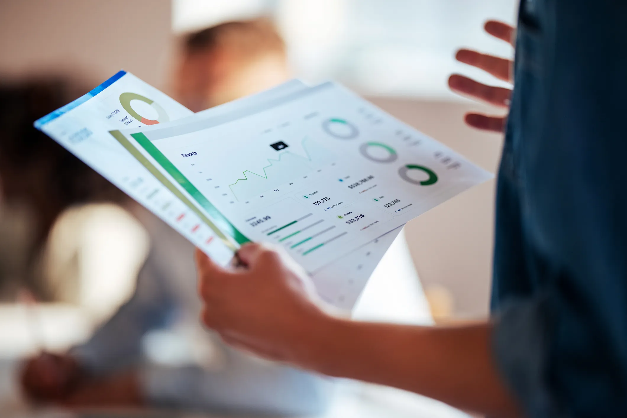 a persons hand holding reports in a meeting
